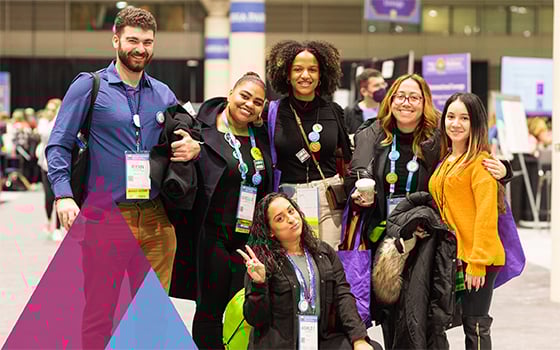 Six members pose and smile at ASHA convention. One member kneeling in front holds up two fingers.